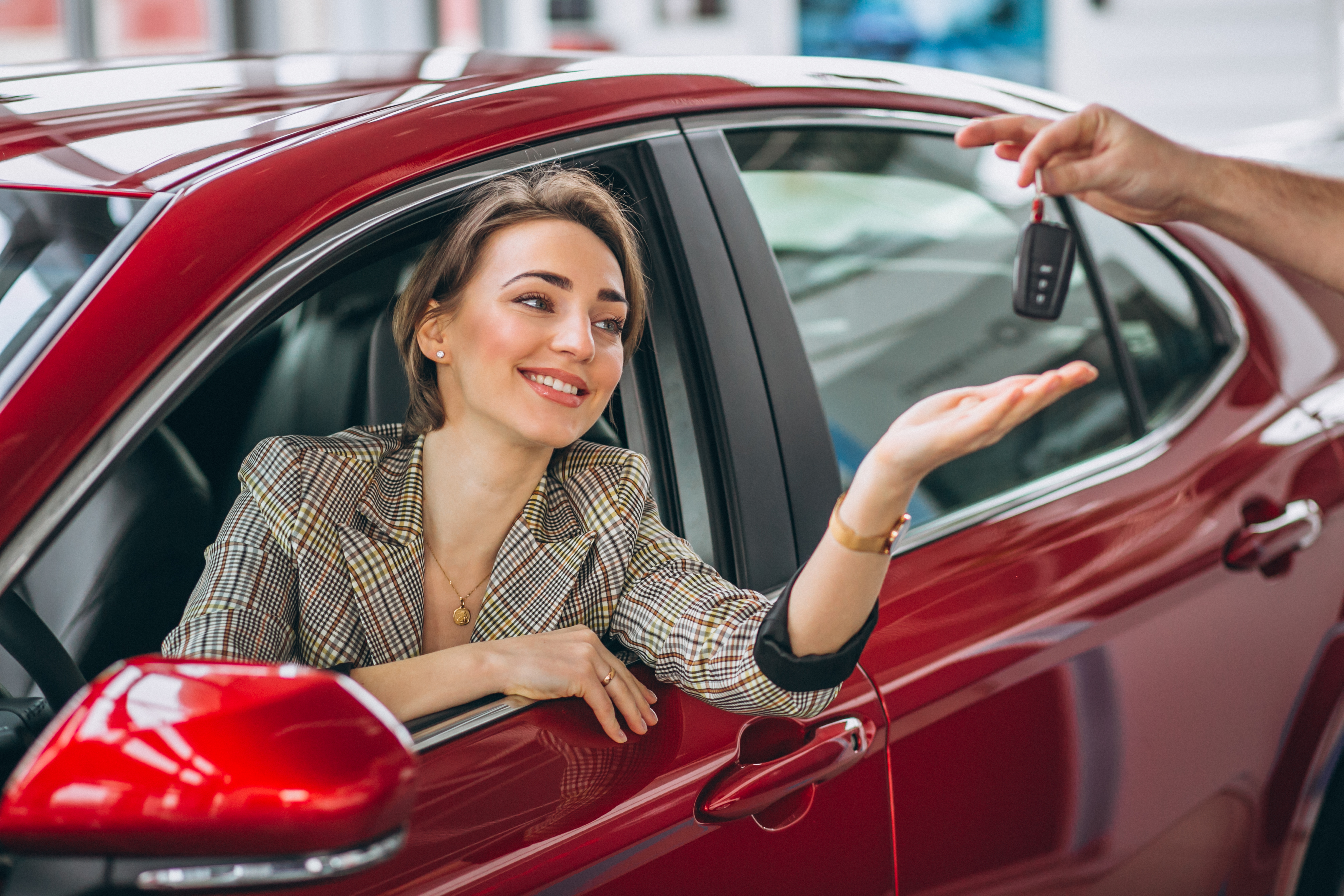 Woman sitting in red car receiving keys